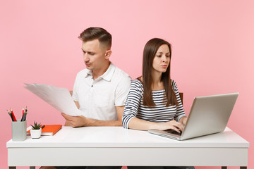 Two young angry business woman man colleagues sit work at white desk with contemporary laptop...