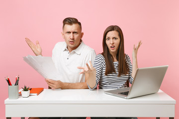 Two young angry business woman man colleagues sit work at white desk with contemporary laptop...