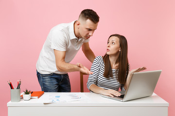 Two young angry business woman man colleagues sit work at white desk with contemporary laptop isolated on pastel pink background. Achievement career concept. Copy space advertising, youth co working.
