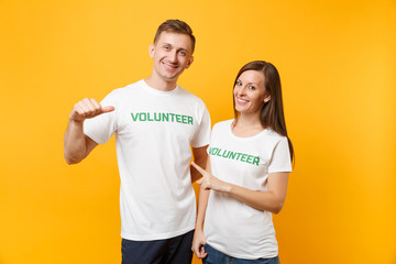 Portrait of young colleagues couple in white t-shirt with written inscription green title volunteer...