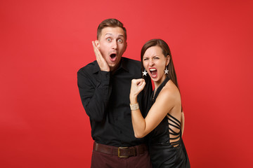 Fun expression young couple in black clothes shirt dress celebrating birthday holiday party isolated on bright red background. St Valentine International Women Day Happy New Year 2019 concept. Mock up
