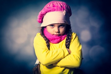 Close-up portrait of adorable sad child girl wearing pink knitted hat
