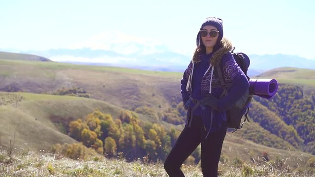 Portrait of woman tourist with backpack, mountains in the background,slow mo