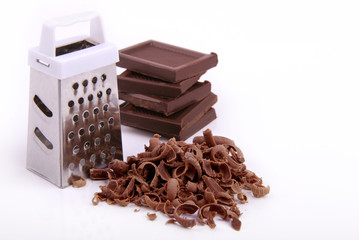 Little grater, pieces of chocolate and shavings on a white isolate.