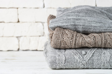 Stack of cozy woolen clothes on white.