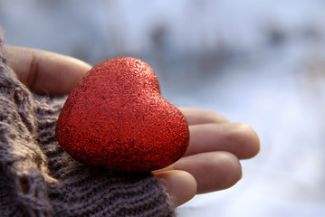 Decorative red heart on a female palm.