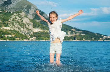 Little girl in clothes having fun in the sea.