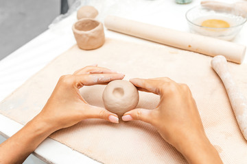 A close-up of a female potter hands holding a brown clay, workshop class