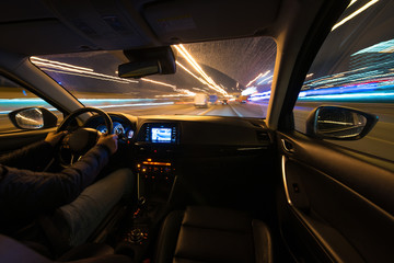 Fototapeta premium Driving in the night landscape, hands on the wheel. Raindrops.