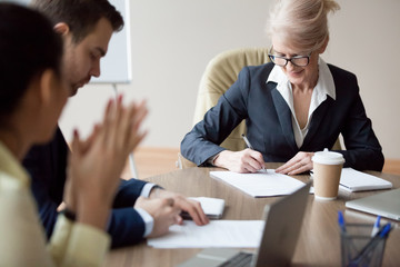 Business partners sign agreement in office after successful boardroom meeting, middle aged employee...