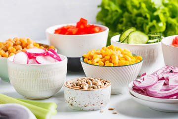 Assortment ingredients for healthy vegetarian salad in different portion bowls on a table. The concept of fitness and vegan food.