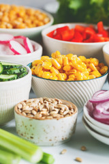 Assortment ingredients for healthy vegetarian salad in different portion bowls on a table. The concept of fitness and vegan food.