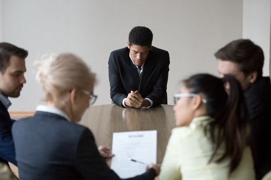 Worried black applicant feel nervous waiting for recruiters decision, anxious African American job candidate upset and insecure at interview, employers have discussion considering employee resume