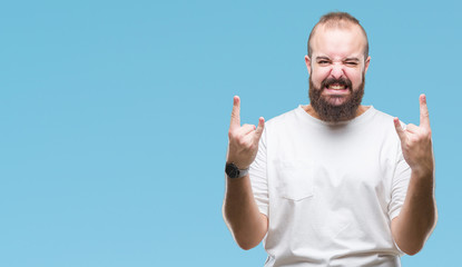 Young caucasian hipster man wearing casual t-shirt over isolated background shouting with crazy expression doing rock symbol with hands up. Music star. Heavy concept.