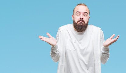 Naklejka premium Young caucasian hipster man wearing sport clothes over isolated background clueless and confused expression with arms and hands raised. Doubt concept.