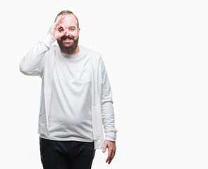 Young caucasian hipster man wearing sport clothes over isolated background doing ok gesture with hand smiling, eye looking through fingers with happy face.