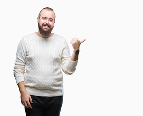 Young caucasian hipster man wearing winter sweater over isolated background smiling with happy face looking and pointing to the side with thumb up.