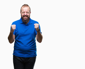 Young caucasian hipster man wearing blue shirt over isolated background excited for success with arms raised celebrating victory smiling. Winner concept.