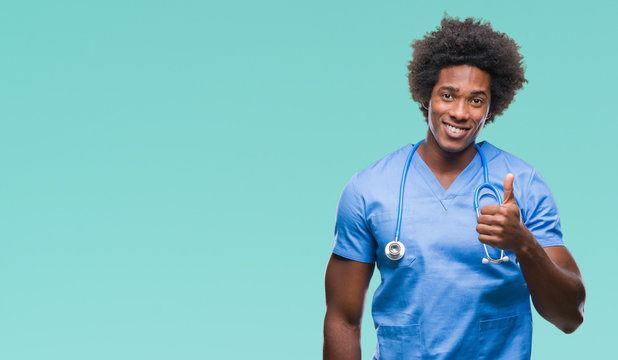 Afro american surgeon doctor man over isolated background doing happy thumbs up gesture with hand. Approving expression looking at the camera with showing success.