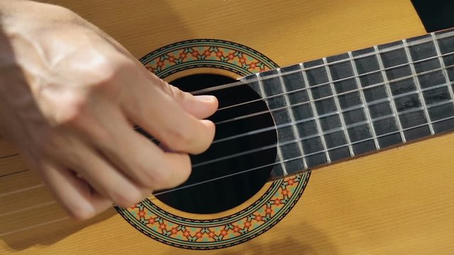 Close up shot of guitarist's hand. He plays on acoustic guitar.