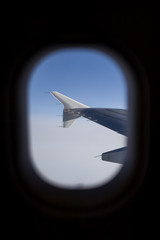 aircraft wing and sky as seen through window of an aircraft
