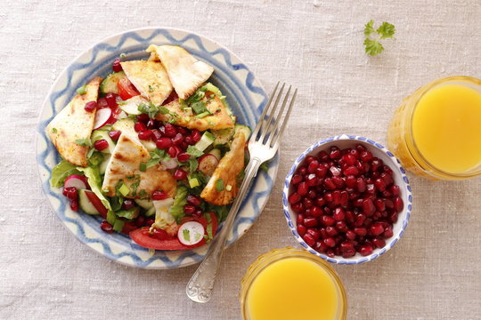 Fattush salad with pomegranate seeds and two glasses of orange juice