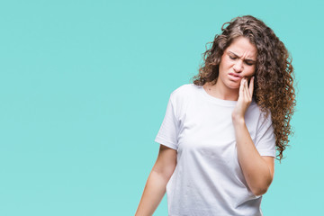 Beautiful brunette curly hair young girl wearing casual t-shirt over isolated background touching mouth with hand with painful expression because of toothache or dental illness on teeth