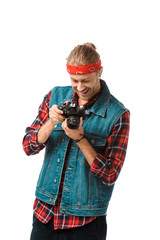 smiling hipster male photographer in denim vest and checkered shirt looking at camera screen isolated on white