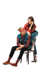 Fototapeta premium cheerful young man sitting on chair while his hipster girl standing behind isolated on white