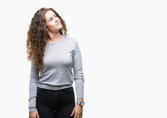 Fototapeta premium Beautiful brunette curly hair young girl wearing a sweater over isolated background looking away to side with smile on face, natural expression. Laughing confident.
