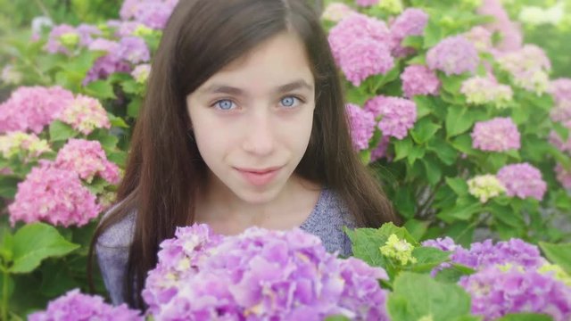 Girl Smells Flower and Looks Up and Smiles. a close up view of a girl in a group of flowers and smells one and looks up at camera and smiles