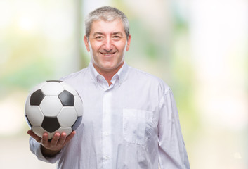 Handsome senior man holding soccer football ball over isolated background with a happy face...
