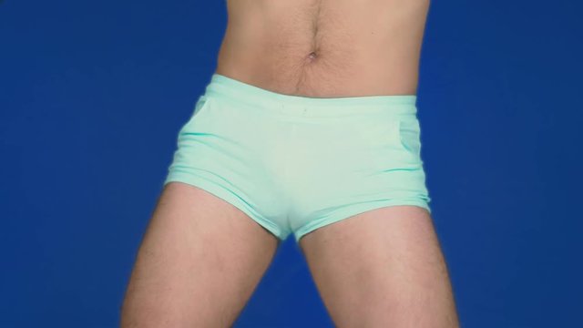 The concept of humor and parodies. A man in a pink t-shirt and blue shorts dances and takes off his jersey, exposing his hairy belly.