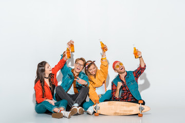 cheerful stylish hipsters sitting with skateboard and holding beer bottles © LIGHTFIELD STUDIOS