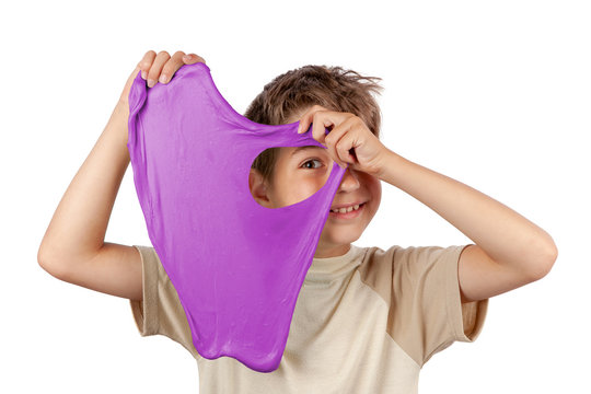 Cheerful boy holding a purple slime toy and looking through its hole. Studio isolated on white background.