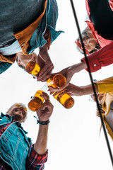 bottom view of happy friends clinking with beer bottles together