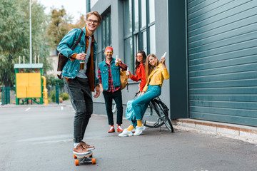 young hipsters with longboard and bike having fun on street