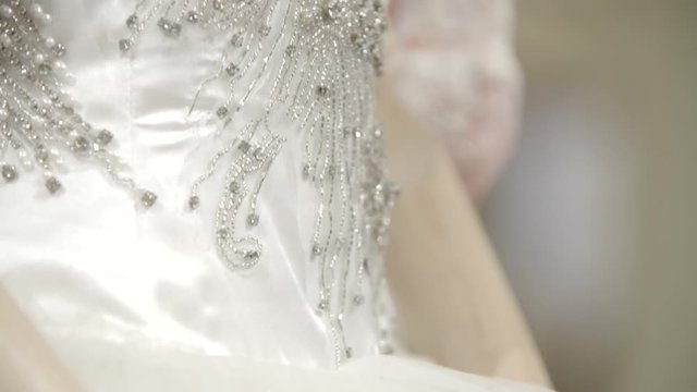 A white lacy dress on a female mannequin. Dettail of a wedding gown with necklace made of pearls. Fashion concept.
