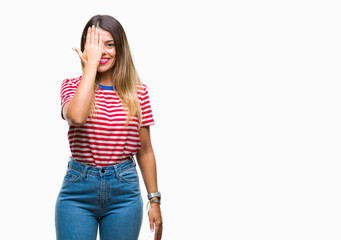Young beautiful woman casual look over isolated background covering one eye with hand with confident smile on face and surprise emotion.