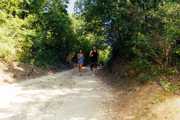 Athletic couple running together on forest trail