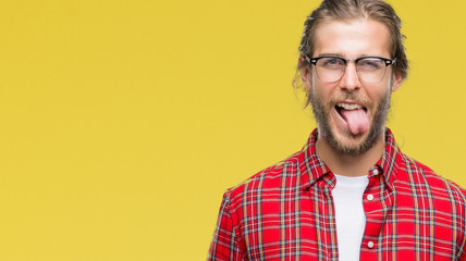 Obraz premium Young handsome man with long hair wearing glasses over isolated background sticking tongue out happy with funny expression. Emotion concept.