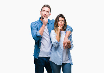 Naklejka premium Young couple in love over isolated background with hand on chin thinking about question, pensive expression. Smiling with thoughtful face. Doubt concept.