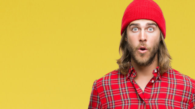 Young handsome man with long hair wearing red cap over isolated background afraid and shocked with surprise expression, fear and excited face.