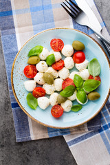 Delicious caprese salad with ripe cherry tomatoes and mini mozzarella cheese balls with fresh basil leaves.