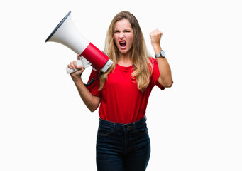 Young beautiful blonde woman yelling through megaphone over isolated background annoyed and frustrated shouting with anger, crazy and yelling with raised hand, anger concept