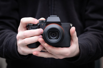 Fototapeta premium Mirrorless digital camera in hand of a young man. Clean image with no brands or signs