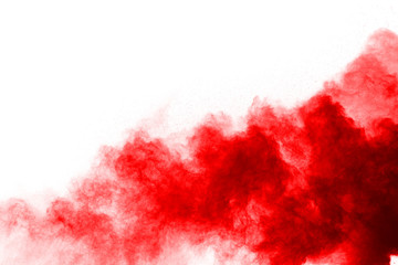 Freeze motion of red powder exploding, isolated on white background. Abstract design of red dust...