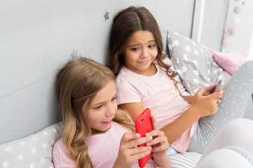 Activities for pajama party. Girls kids best friends or sisters wear pajama busy with smartphones. Children in pajama interact with smartphones. Technologies for kids generation. Pajama party ideas