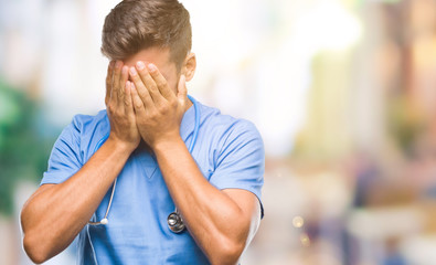 Young handsome doctor surgeon man over isolated background with sad expression covering face with hands while crying. Depression concept.