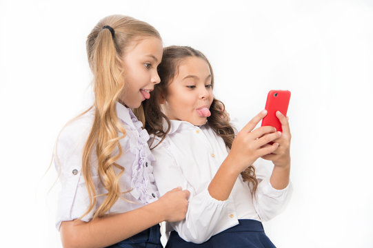 Online entertainment concept. Schoolgirls use smartphone check social networks. Send message friend. Online communication. Send selfie social network. Grimace for funny selfie. Posting funny photos
